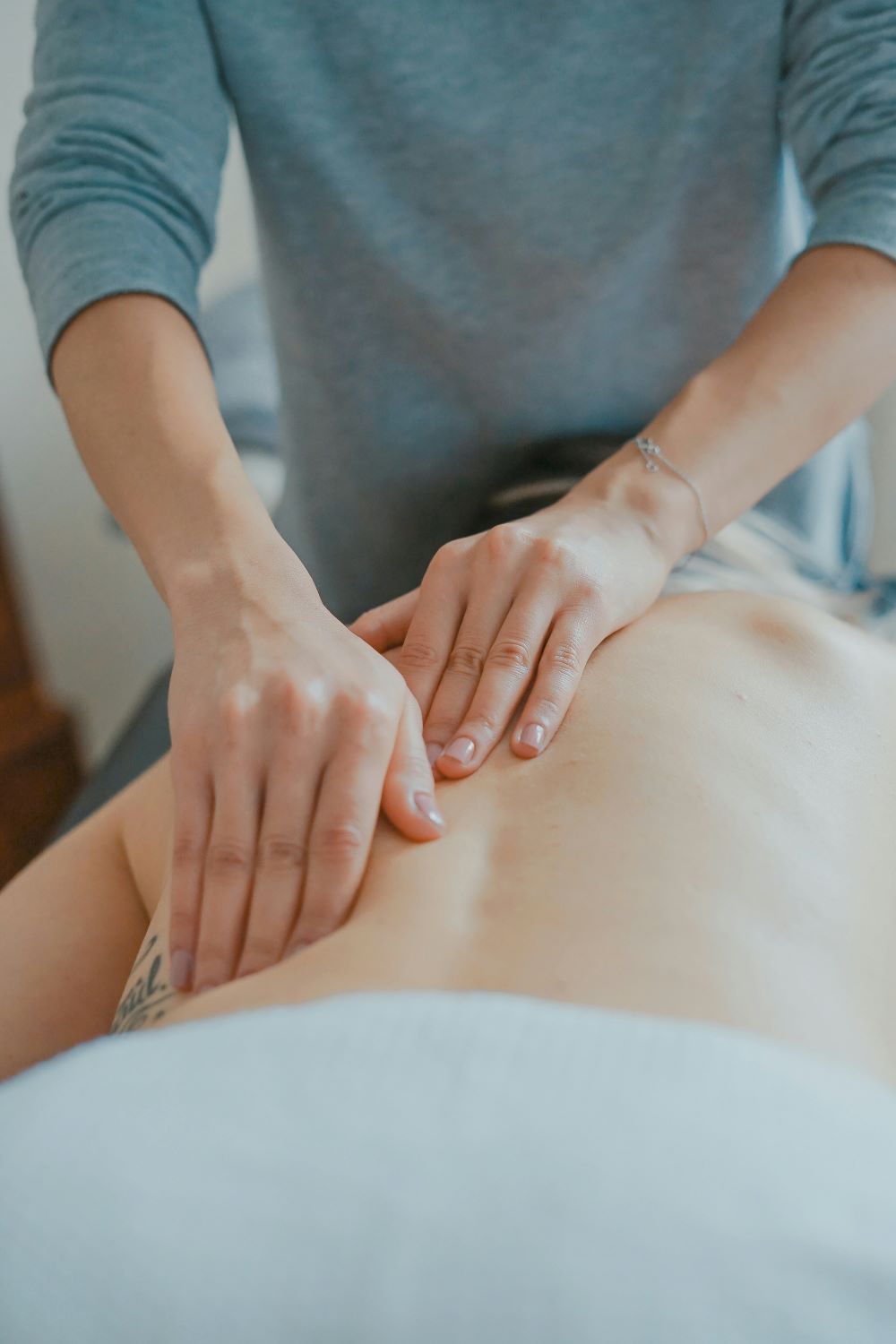 Fyzioterapeut provádí masáž pomocí měkkých technik.